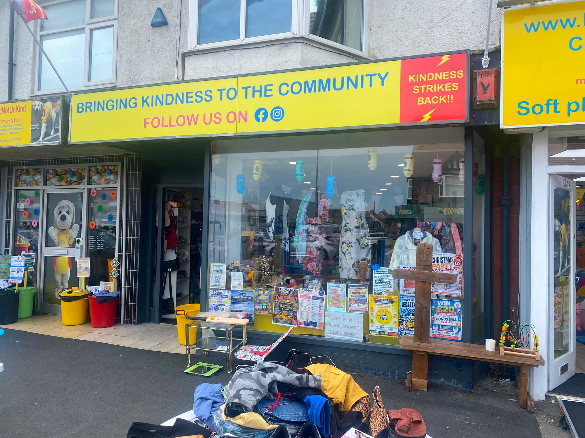 The charity shop next door, under a yellow sign reading 'Bringing kindness to the community'.