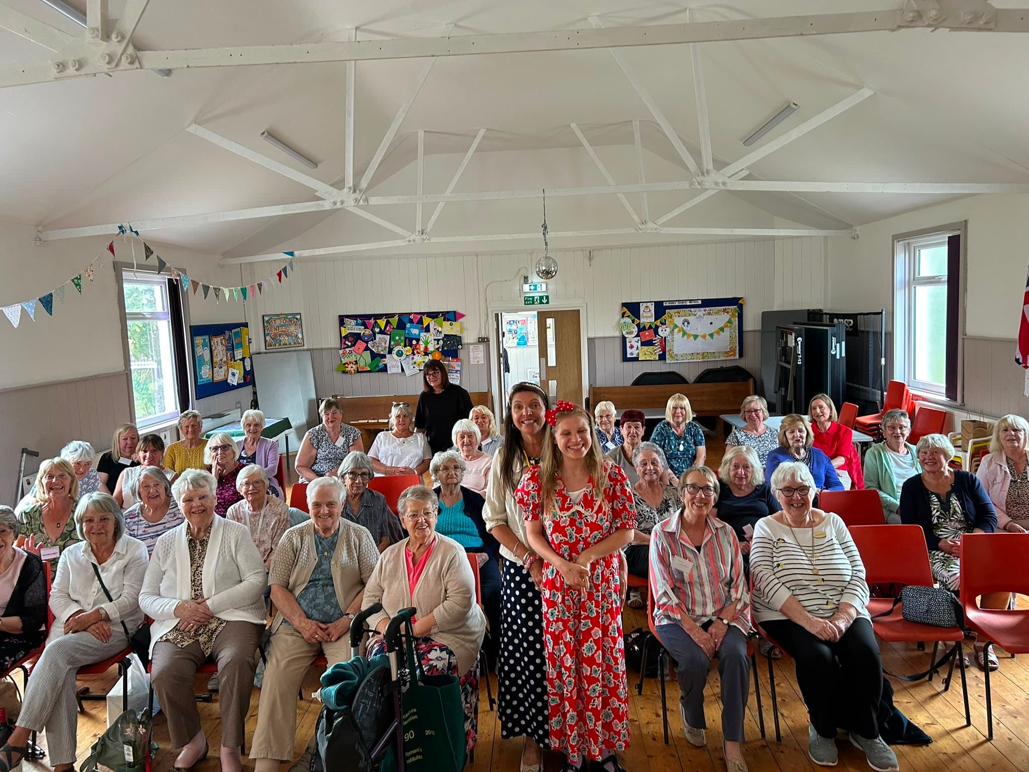 A hall full of Thornton Women's Institute members, with two of the Kindness Counts UK team standing among them.